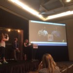 Nigel Poor, left, shoots a video during her Podquest finalists' presentation at Podcast Movement 2016 in Chicago. On the screen are Earlonne Woods and Antwan Williams, Poor's partners in producing the Ear Hustle podcast.