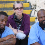 The three producers of the Ear Hustle podcast sit on stairs at San Quentin Prison in California.