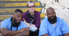 The three producers of the Ear Hustle podcast sit on stairs at San Quentin Prison in California.